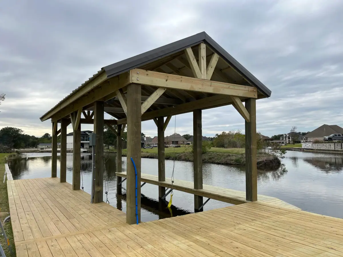 Gable-roof boathouse with a boat lift on a canal, treated pine on a new dock