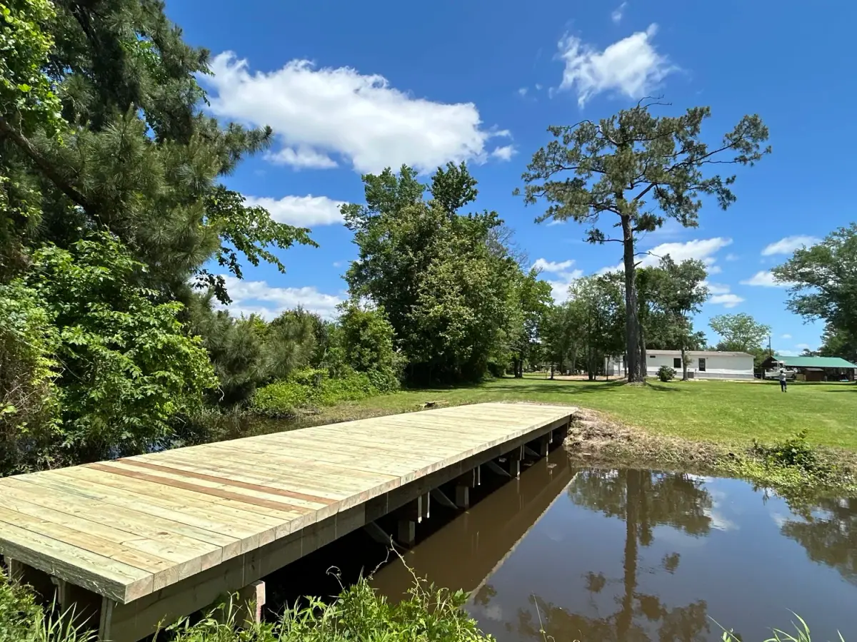 Long treated-pine bridge over water to a yard
