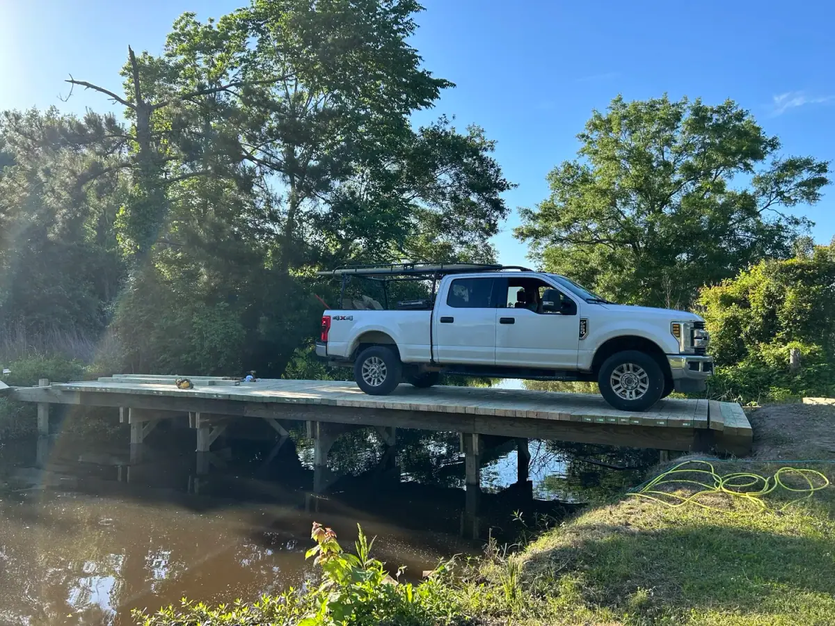 The crew’s white pickup parked on a timber bridge over a creek