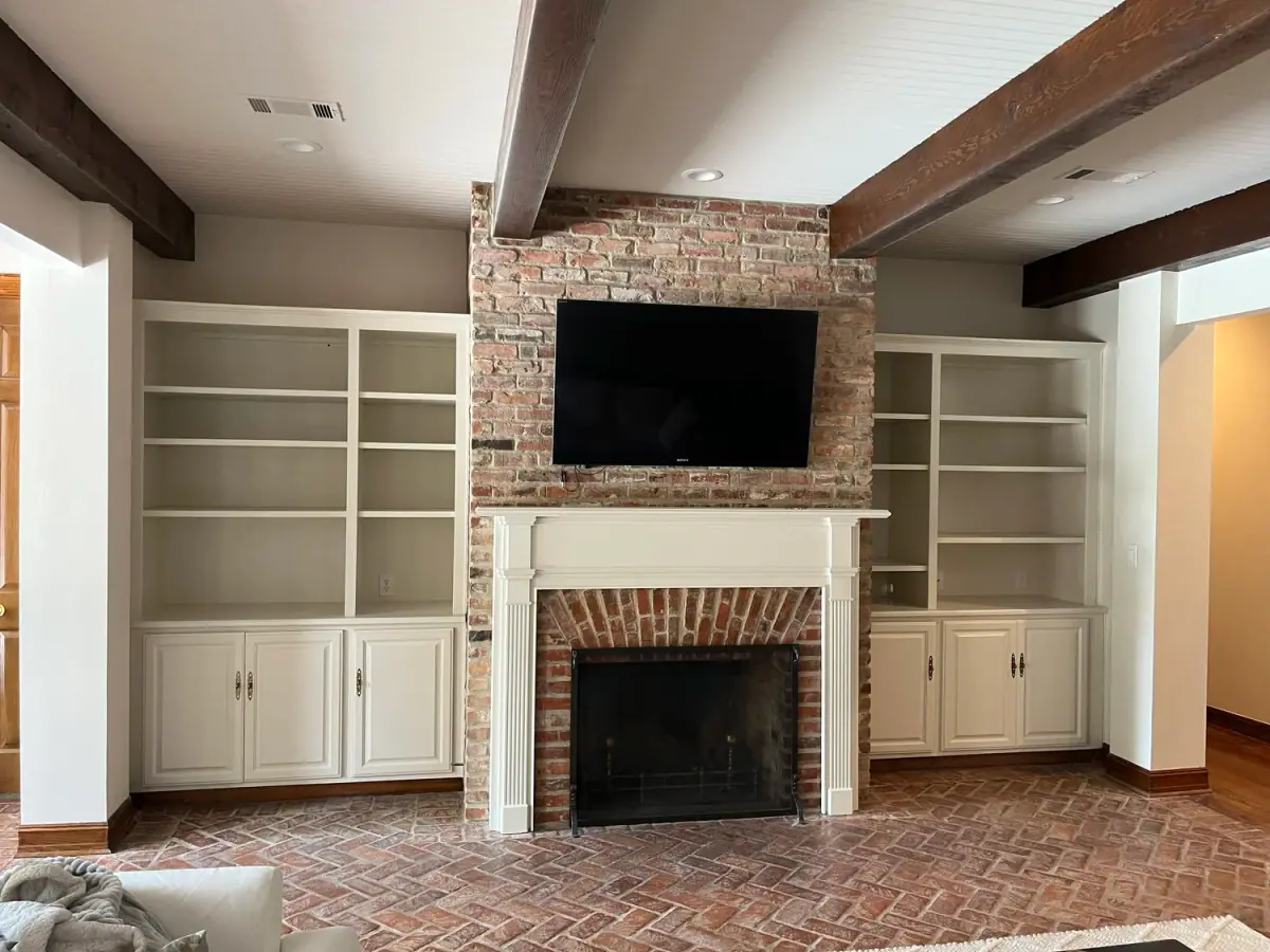 Built-in shelving around a brick fireplace with a TV niche