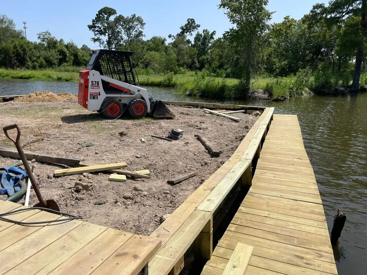 Timber bulkhead under construction with a skid steer on the bank