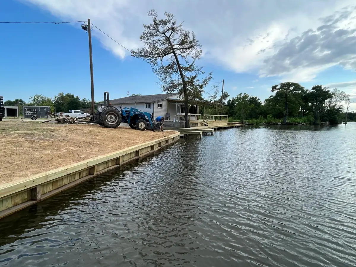 New treated-pine bulkhead along a bayou bank with a tractor on the shore