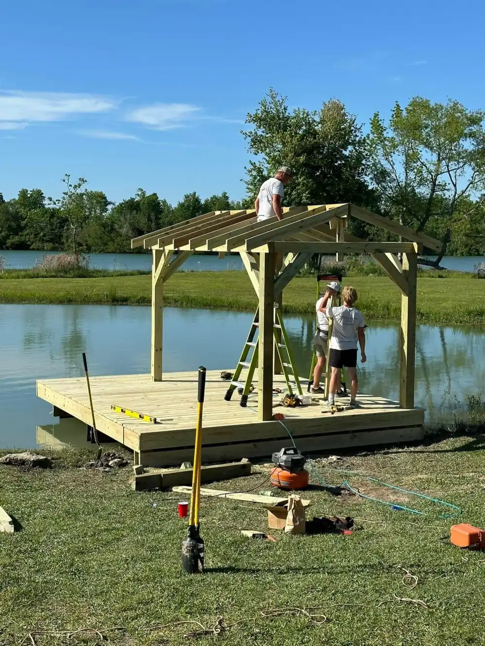 Matt and two crew members framing a gable roof on a new dock over a pond