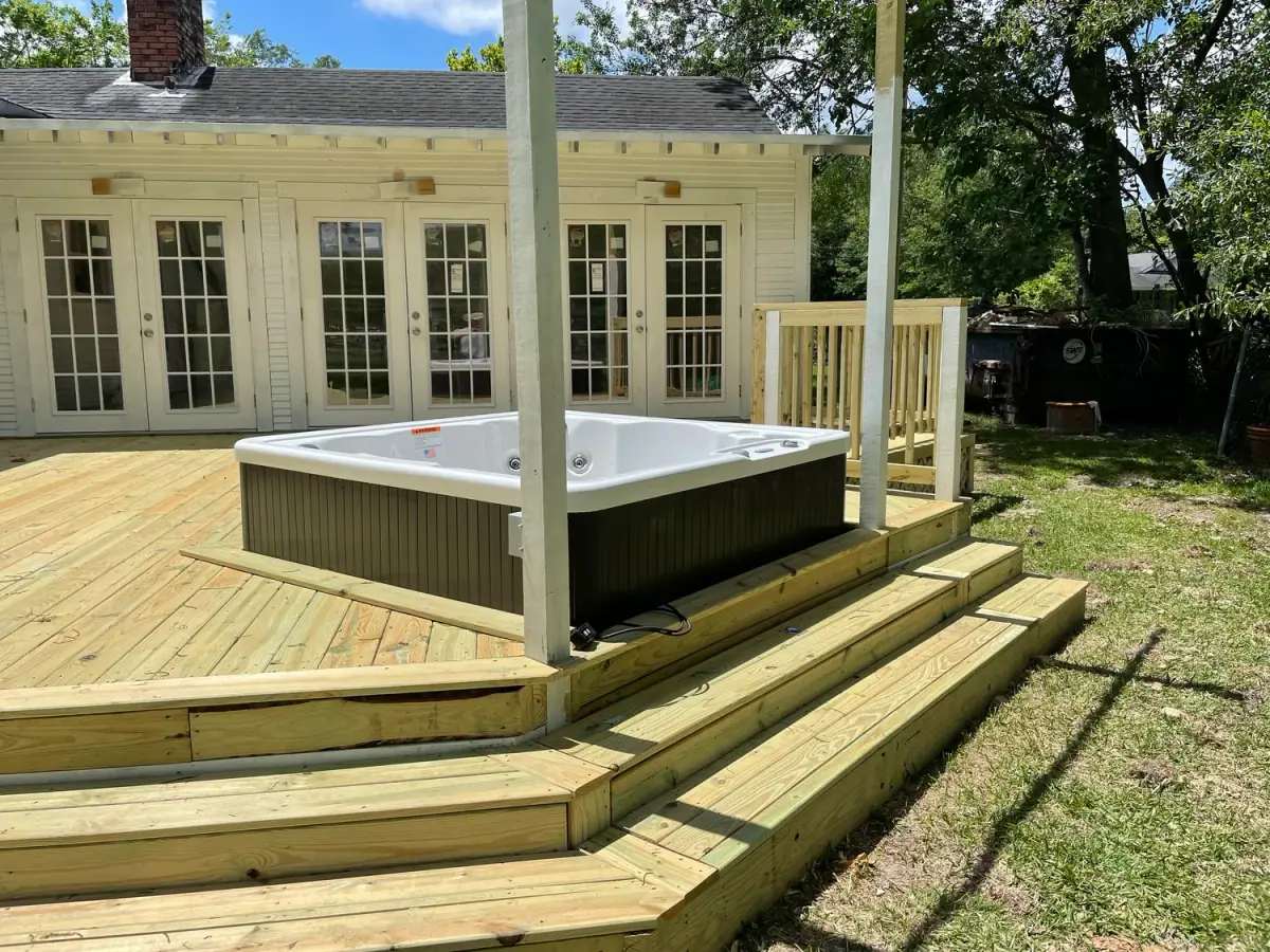 Treated-pine deck with a hot tub behind a house