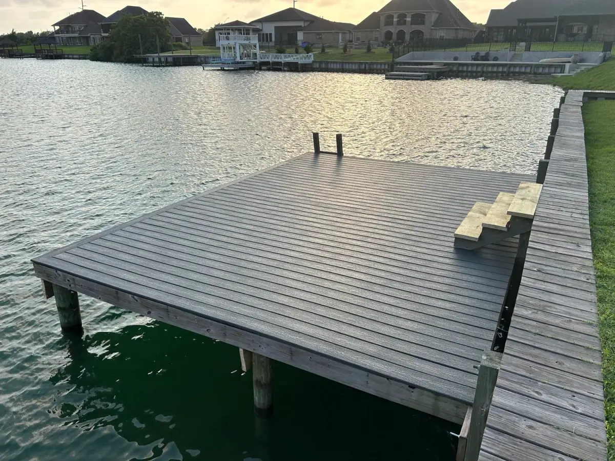 Grey composite dock on a bulkhead with palms and houses across the water