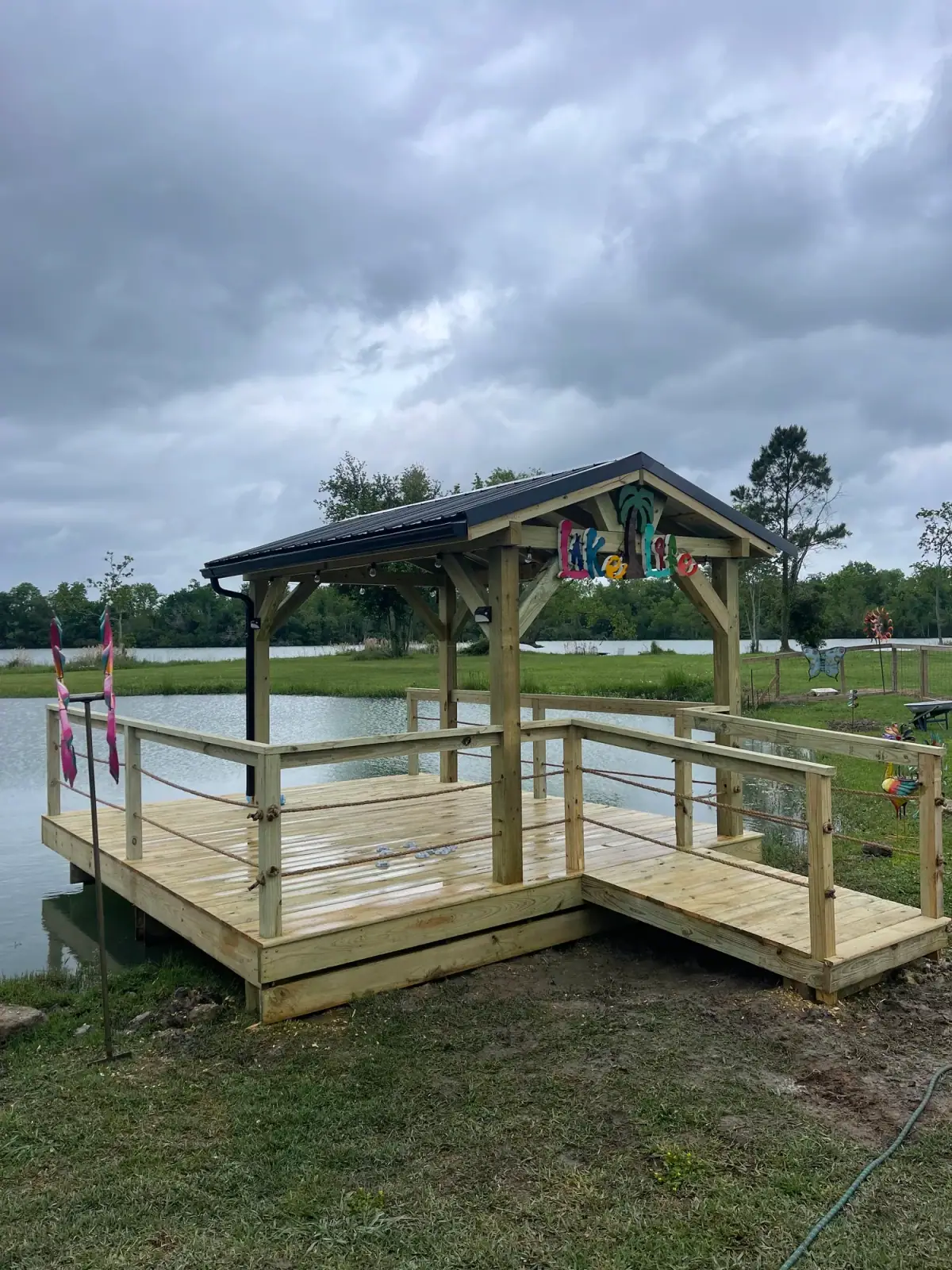 Dock with a small gable pavilion and railing on a lake