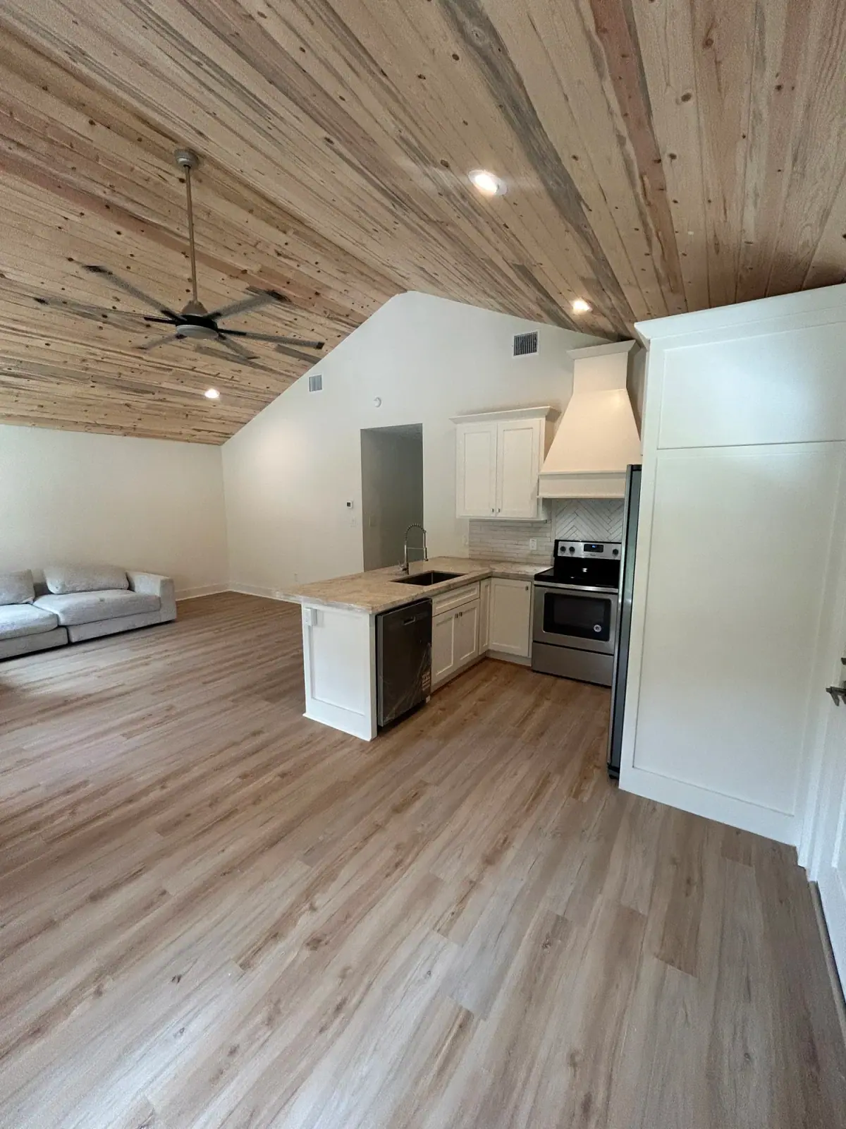 Open kitchen and living room with a pine tongue-and-groove ceiling