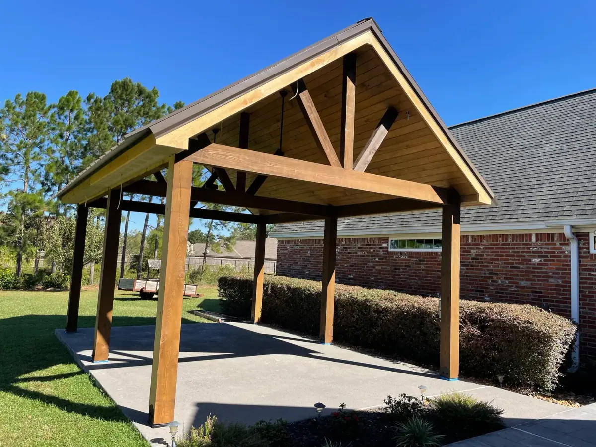 Large heavy-timber gable pavilion beside a brick house
