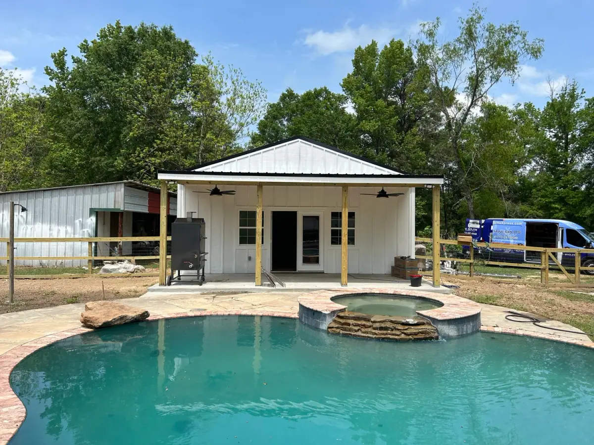 Small pool house with a metal roof beside a new pool and spa